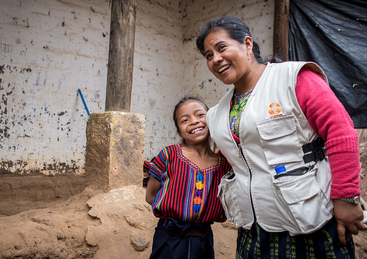 A female CARE staffer smiles with a young girl.